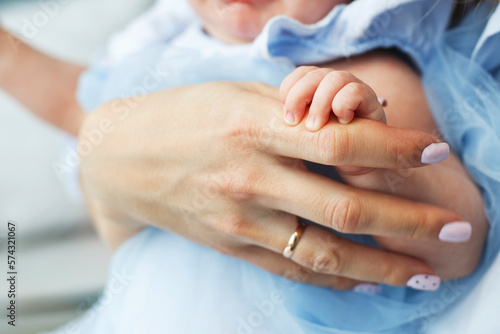 Mother holds the baby in her arms and holds her hand
