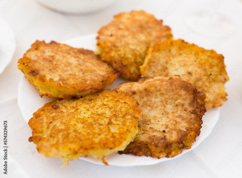 Fried grated potato pancakes with sour cream on white plate Fried grated potato pancakes with sour cream on white plate