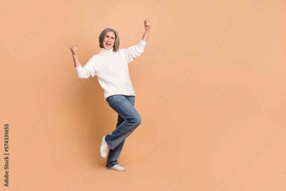 Full length photo of overjoyed business woman mature aged gray hair stylish outfit fists up good profitable sales isolated on beige color background