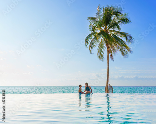 Mother and son At Luxury Resort On Summer Vacation. People Relaxing Together In Edge Swimming Pool Water, Enjoying Beautiful Sea View. Travel. Relationship, Family.