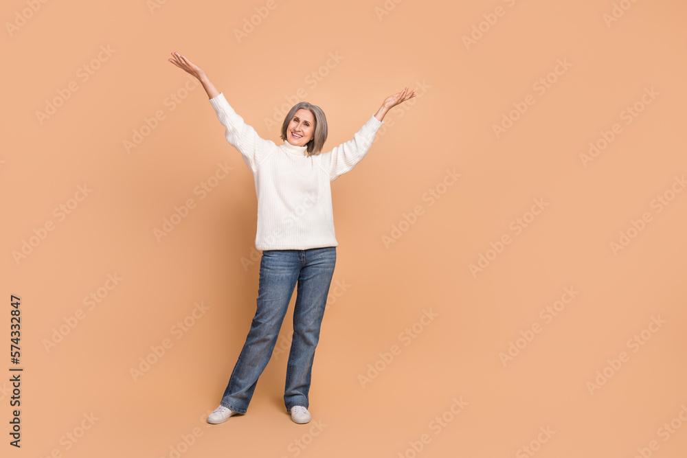 Full body size photo of attractive pretty cheerful woman wear white sweater raise arms up celebrate good mood day isolated on beige color background Full body size photo of attractive pretty cheerful woman wear white sweater raise arms up celebrate good mood day isolated on beige color background