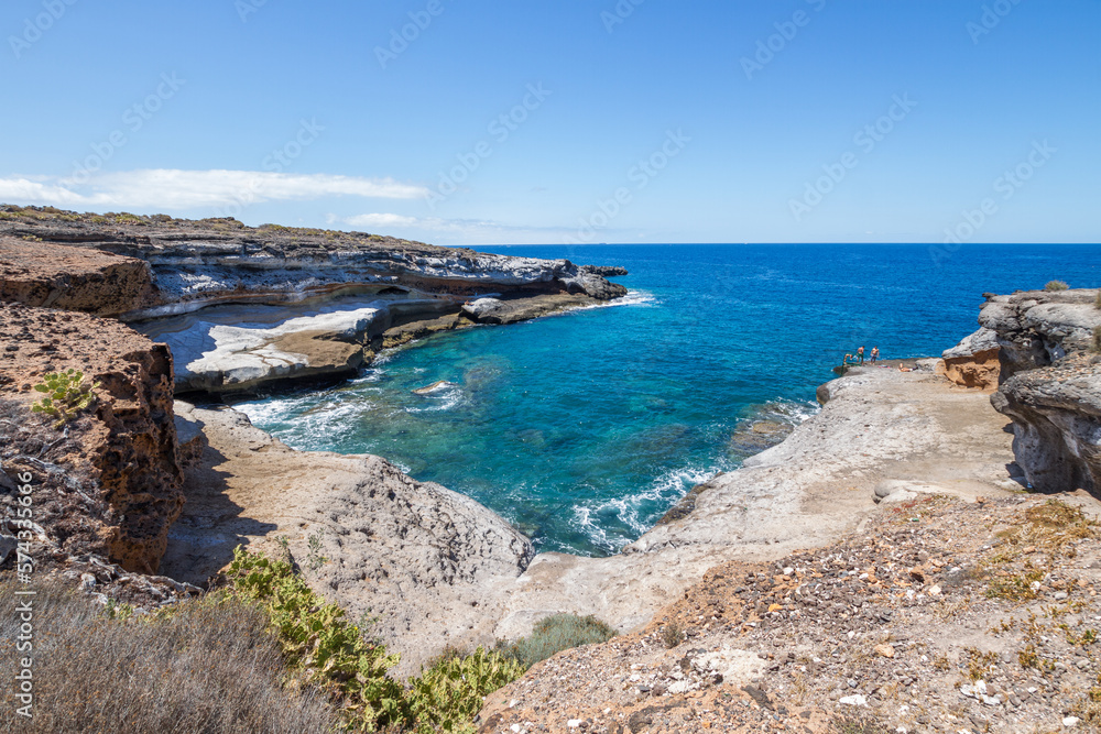 Views of a volcanic rocky cliff. Turquoise ocean. Gray volcanic rock formation. La Caleta, Tenerife, Canary Islands Spain.
