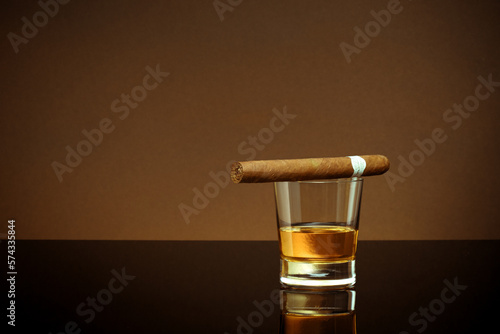 Closed up view of glass of whiskey with cigar on top on white back