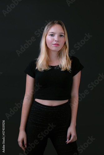 Beautiful young caucasian girl on dark background. Young blond hair female fashion model on black background. Fashion photoshoot.