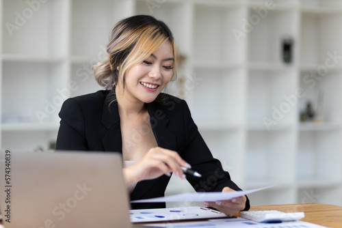 Female business accountant working with laptop and financial documents analyzing budget with calculator.