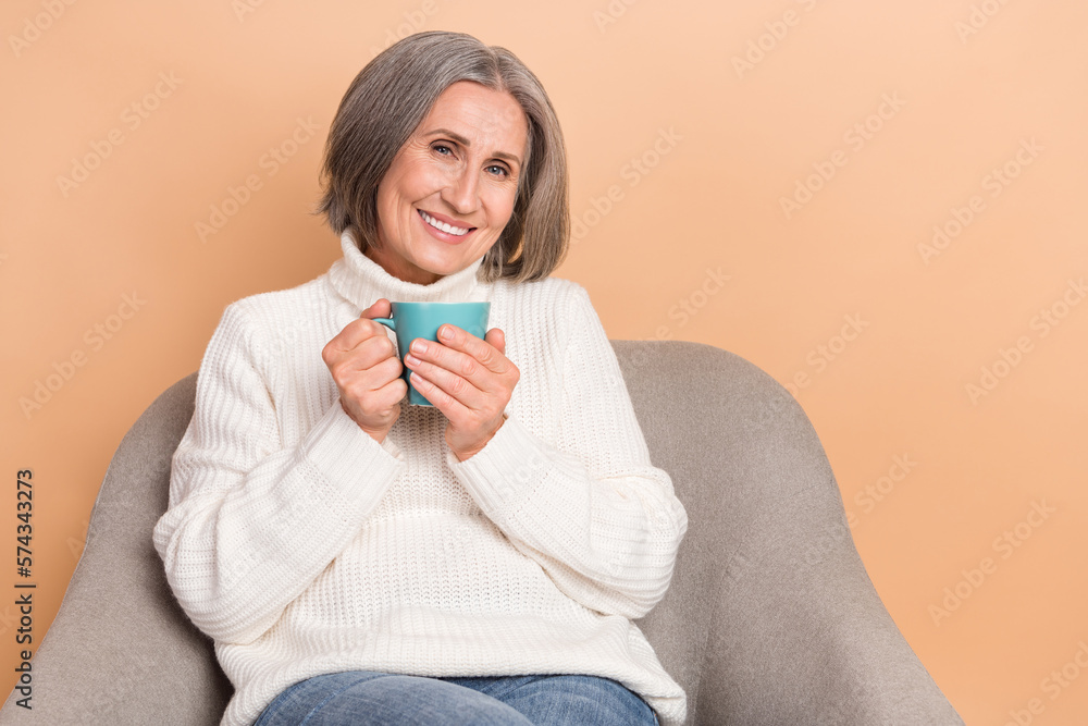 Photo of sweet shiny woman wear knitted pullover drinking coffee empty space isolated beige color background Photo of sweet shiny woman wear knitted pullover drinking coffee empty space isolated beige color background