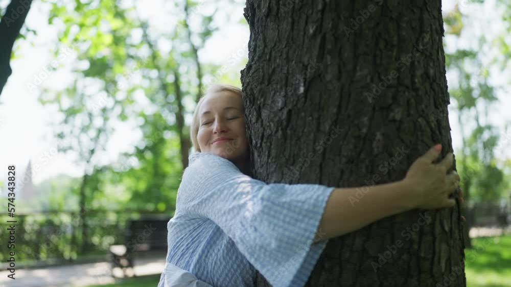 Senior woman hugging tree in park, environmental activist, green politics Senior woman hugging tree in park, environmental activist, green politics