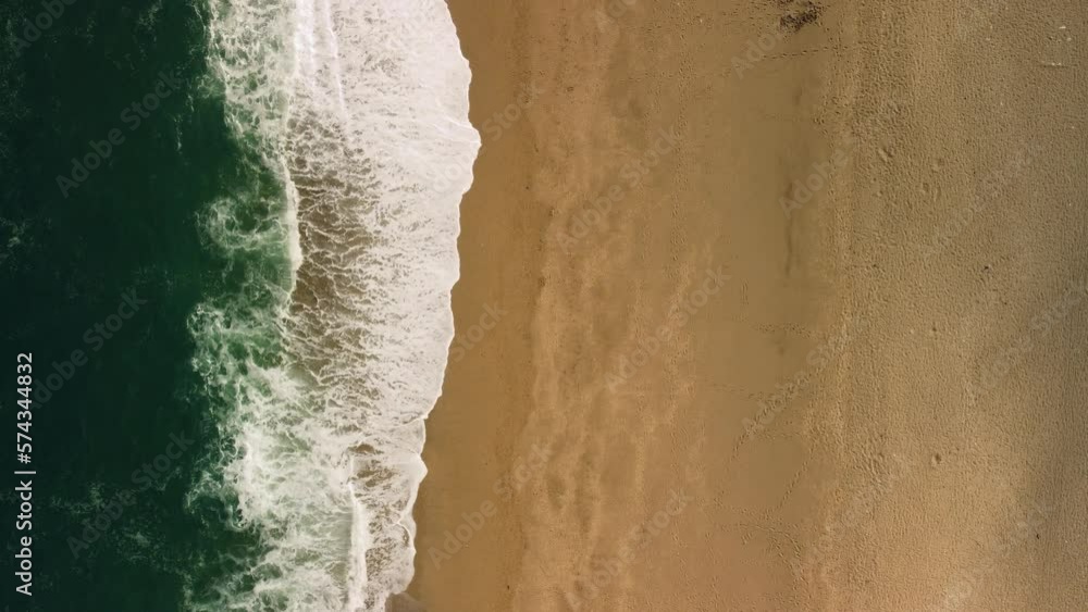 A birds eye view of waves washing a shore in Devon Uk. A quiet beach at summertime A birds eye view of waves washing a shore in Devon Uk. A quiet beach at summertime