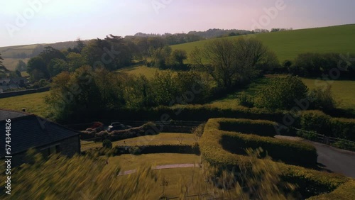 A drone shot flying out of living room double doors to the garden and landscape beyond. Sunny day and green trees and fields. Shot in Stokenham Devon UK photo