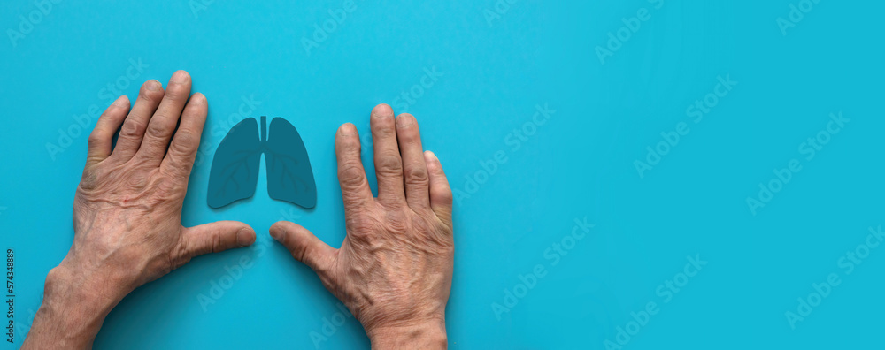 Obraz premium hands of a pensioner and the symbol of the organ lungs on a blue background, banner, copyspace . the concept of lung health, the harm of smoking,treatment of covid, defeat of the disease lung cancer