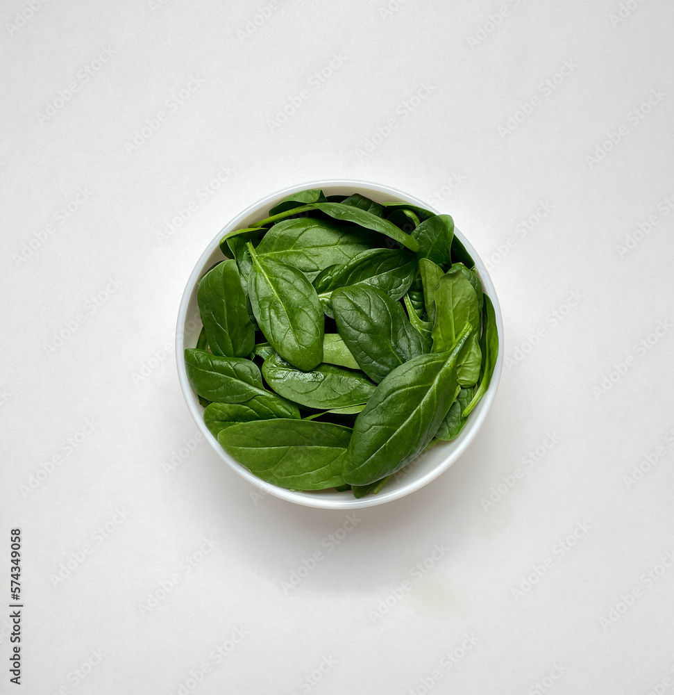 Spinach leaves in white plate isolated on white background. Copy space, top view. Spinach leaves in white plate isolated on white background. Copy space, top view.