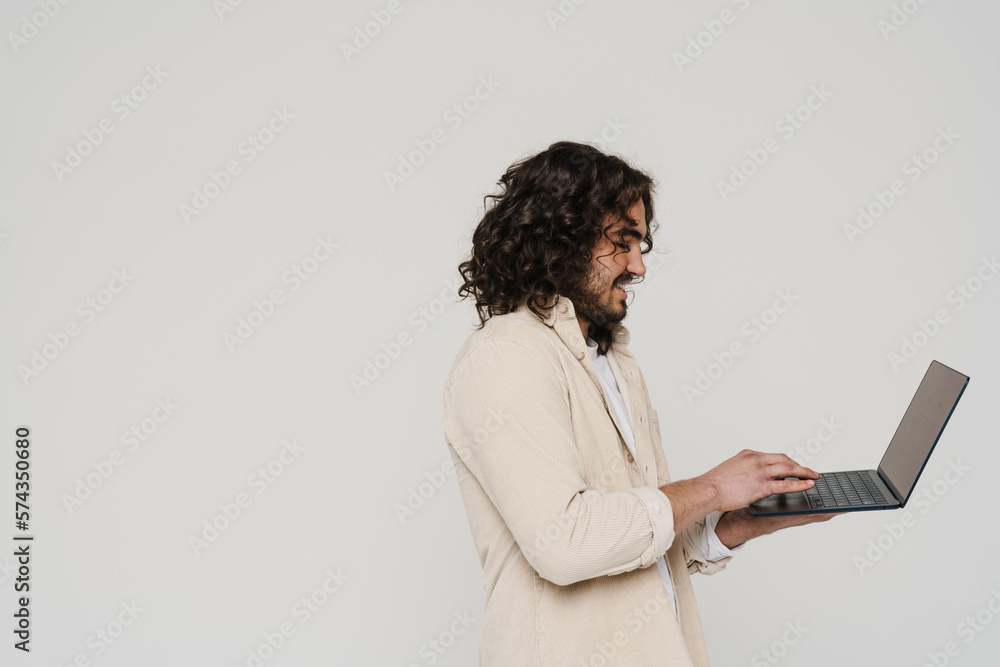 Profile of smiling hispanic man working on laptop isolated over white background Profile of smiling hispanic man working on laptop isolated over white background