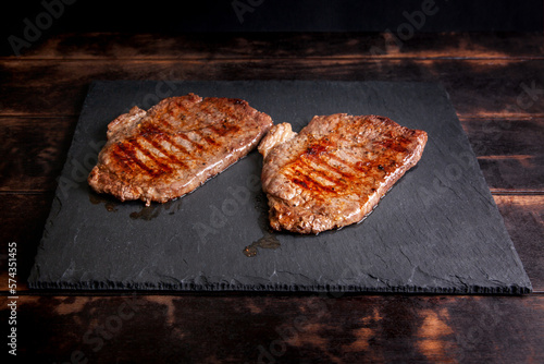 Grilled minute steak of marbled beef on a stone slate board