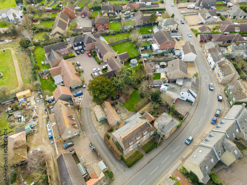 Aerial view of part of a typical English village, showing the main road snaking into the village High Street on the lower left.