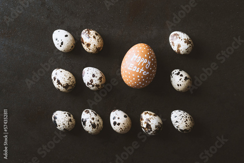 Happy easter eggs flat lay on rustic metal black background. Quail and chicken eggs lined up in a row as a rectangle shape