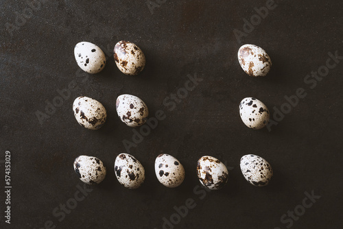 Eggs flat lay on rustic metal black background. Quail and chicken eggs lined up in a row as a rectangle shape