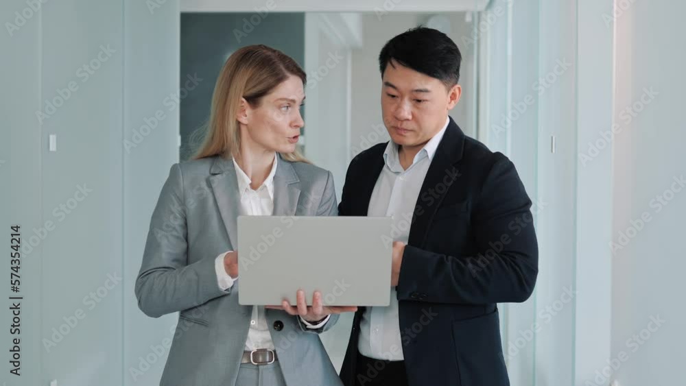 Successful Businesswoman in Stylish Suit Working with Asian Male Adviser. Cheerful Positive Friendly Businesspeople Partners Colleagues Holding Laptop Discuss Ideas. Good Business Relationships. Successful Businesswoman in Stylish Suit Working with Asian Male Adviser. Cheerful Positive Friendly Businesspeople Partners Colleagues Holding Laptop Discuss Ideas. Good Business Relationships.