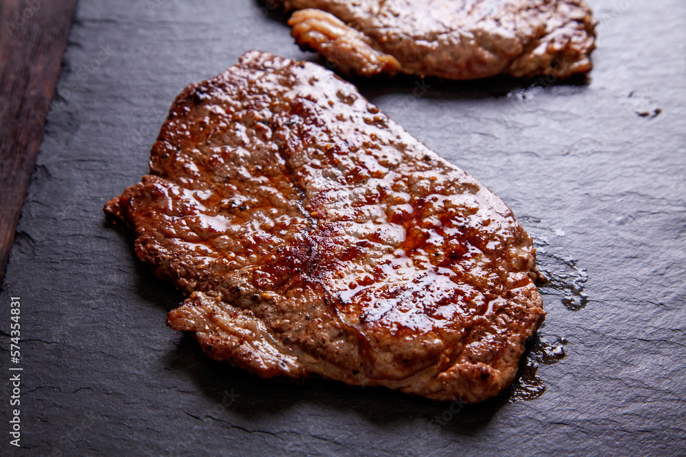Grilled minute steak of marbled beef on a stone slate board, close up