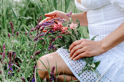Hands of woman picking up wild flowers into a bouquet