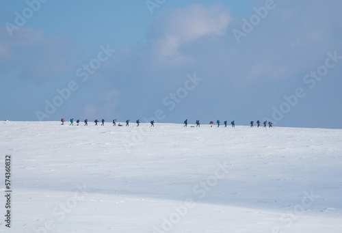 A group of tourists walking in a row on a snowy field