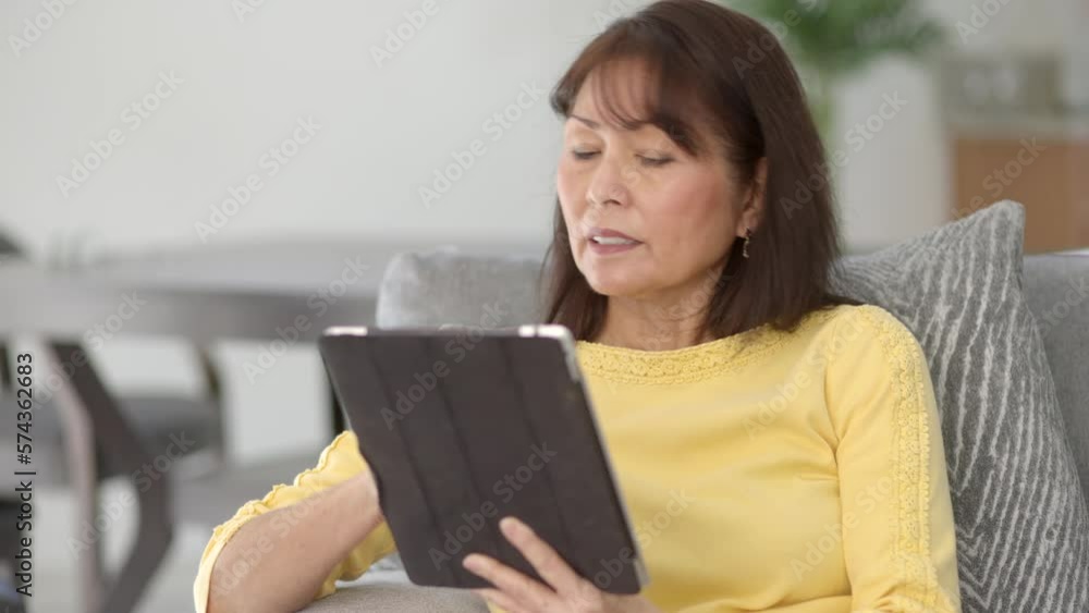 Attractive middle age woman long hair wearing yellow top shopping online with mobile tablet smiling excited with success of purchase waving credit card sitting at comfortable home dining table