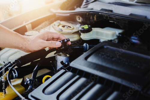 close up of man hand holding cap engine oil tank while checking oil level in a engine , check the oil in a car motor before travel