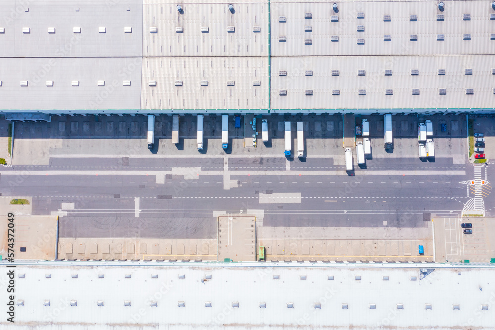 Aerial view of goods warehouse. Logistics center in industrial city zone from above. Aerial view of trucks loading at logistic center stock photo Aerial view of goods warehouse. Logistics center in industrial city zone from above. Aerial view of trucks loading at logistic center stock photo