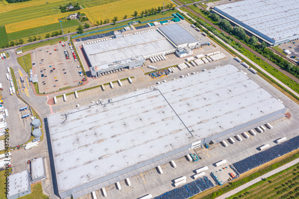 Aerial view of goods warehouse. Logistics center in industrial city zone from above. Aerial view of trucks loading at logistic center stock photo Aerial view of goods warehouse. Logistics center in industrial city zone from above. Aerial view of trucks loading at logistic center stock photo
