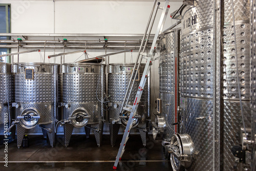 Interno di cantina per vinificazione, viticoltura, affinamento e creazione del mosto. Cisterne in acciaio in ambiente industriale.