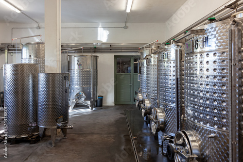Interno di cantina per vinificazione, viticoltura, affinamento e creazione del mosto. Cisterne in acciaio in ambiente industriale.