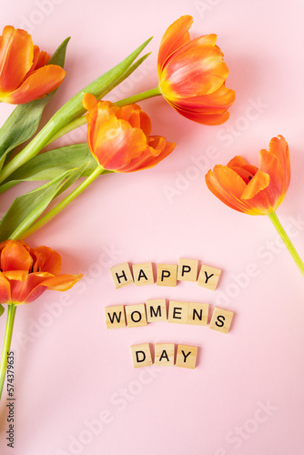 March 8, postcard. Happy Women's Day text sign on orange tulips background. Stylish flat lay with flowers and text, greeting card.