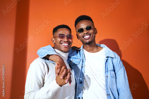 Portrait happy, stylish young gay male couple on orange background