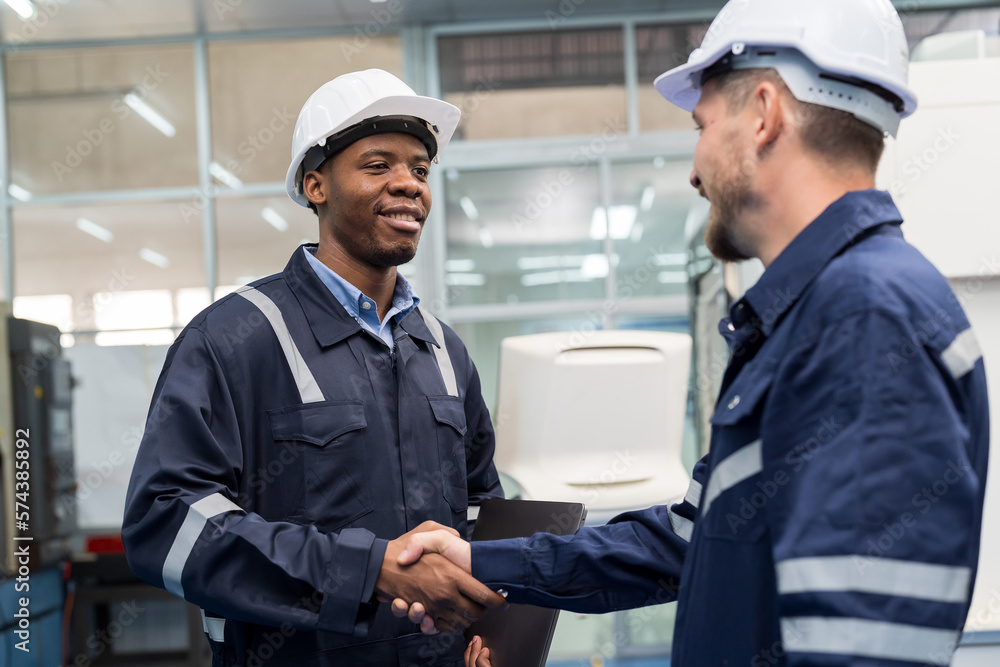 Two male engineer workers shaking hands in the control machine room at factory. Maintenance and repair successful concept Two male engineer workers shaking hands in the control machine room at factory. Maintenance and repair successful concept