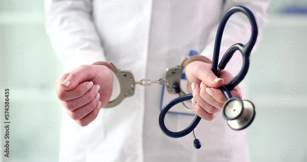 Female doctor or nurse in handcuffs and lab coat holds stethoscope Female doctor or nurse in handcuffs and lab coat holds stethoscope
