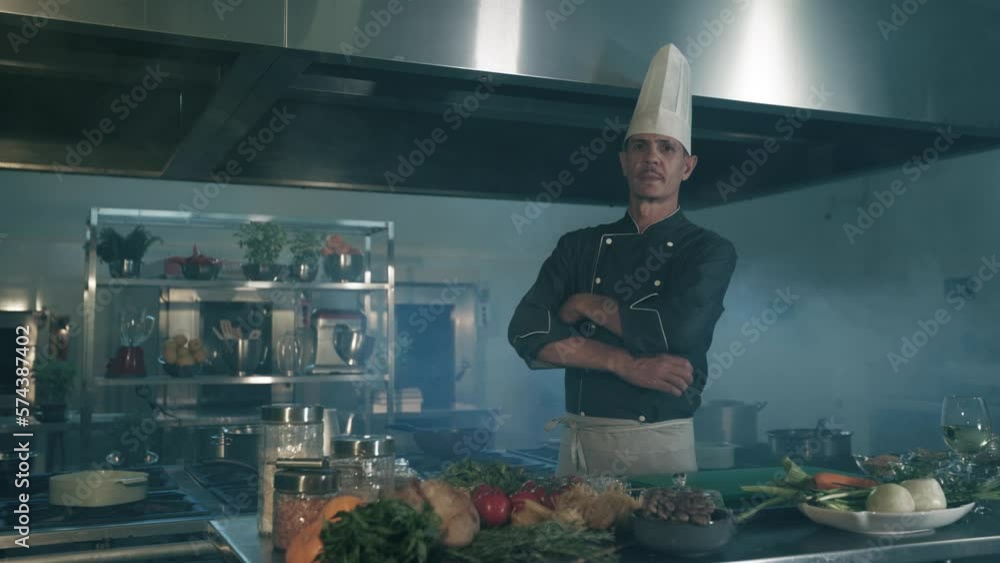 Chef crossing his arms in the kitchen with ingredients on the table Chef crossing his arms in the kitchen with ingredients on the table