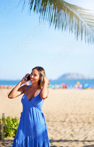 portrait beautiful young brazilian woman smiling and talking on the cell phone on the beach of Ipanema