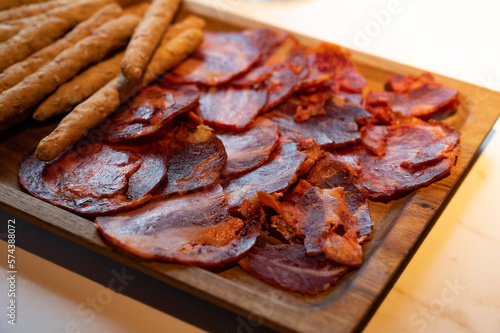 Wooden plate with sliced Spanish tapas, choriso sausage, lomo iberico en bread sticks