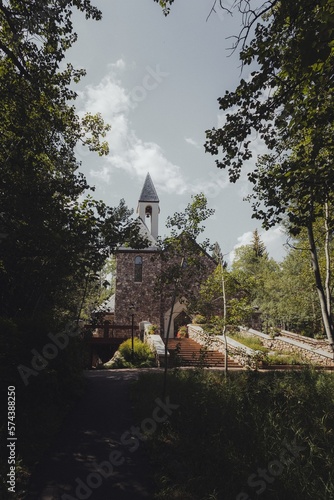 Church chapel Christian religious stone building wedding venue in the mountains with trees and leaves surrounding it.