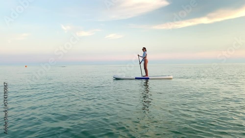 Woman paddleboarder enjoying relaxing floating in calm sea