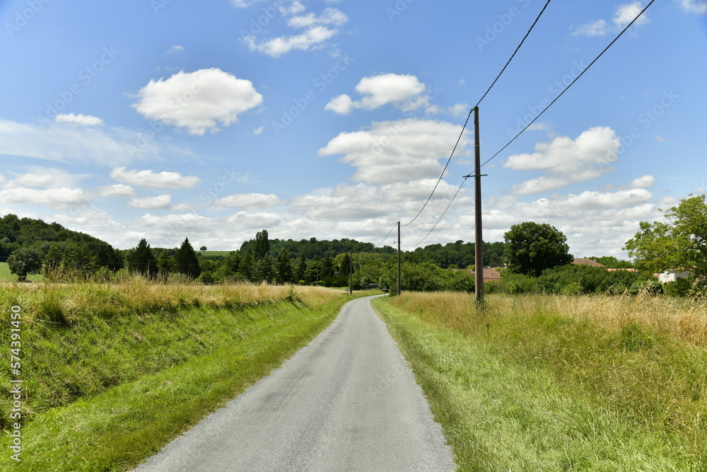 Route secondaire de campagne entre les végétation et champs de blé près du Puy de Versac au Périgord Vert 