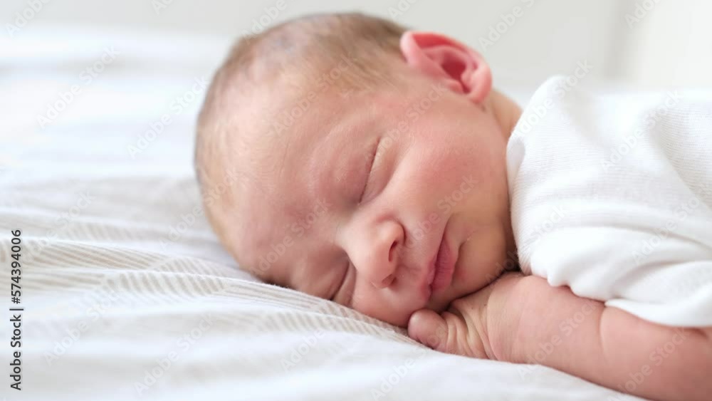 Cute adorable newborn baby boy lying on stomach on white bed at home sleeping,Purity,innosence concept.Close-up of face. Cute adorable newborn baby boy lying on stomach on white bed at home sleeping,Purity,innosence concept.Close-up of face.