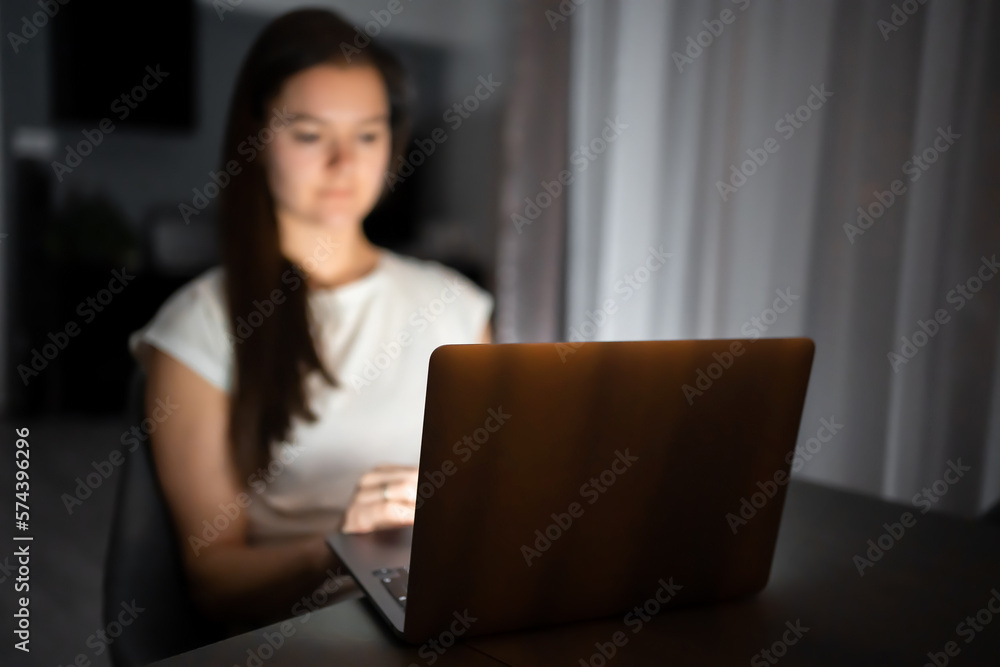 Casual beautiful woman working on a laptop at the night at home.