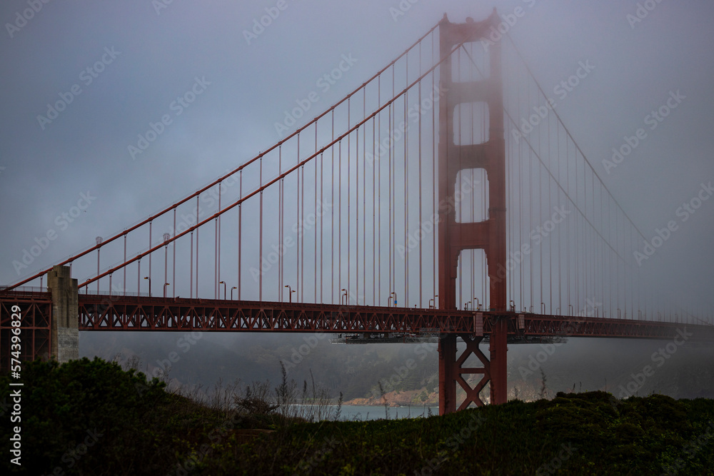 panorama of the golden gate bridge in san francisco during foggy weather; the famous red bridge emerging from behind the clouds, gloomy photo of the golden gate bridge