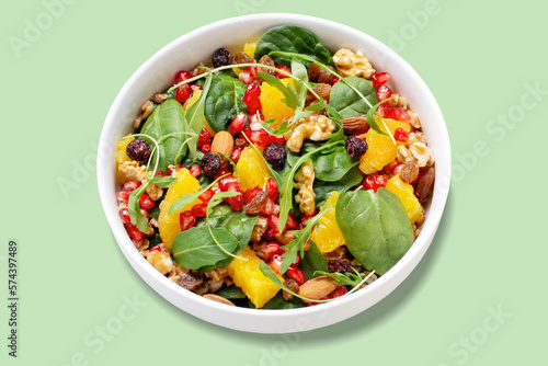 Healthy salad with spelt, oranges, pomegranate seeds. greens and nuts on light background, minimal style photo