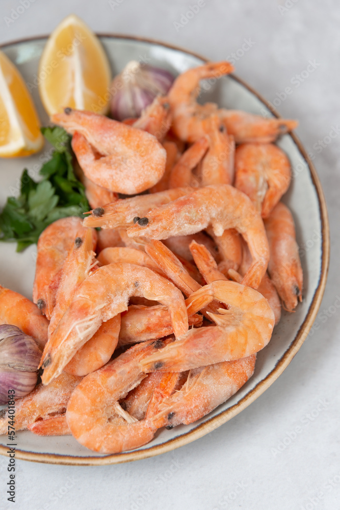 frozen raw shrimps with lemon and garlic on a gray rock background frozen raw shrimps with lemon and garlic on a gray rock background