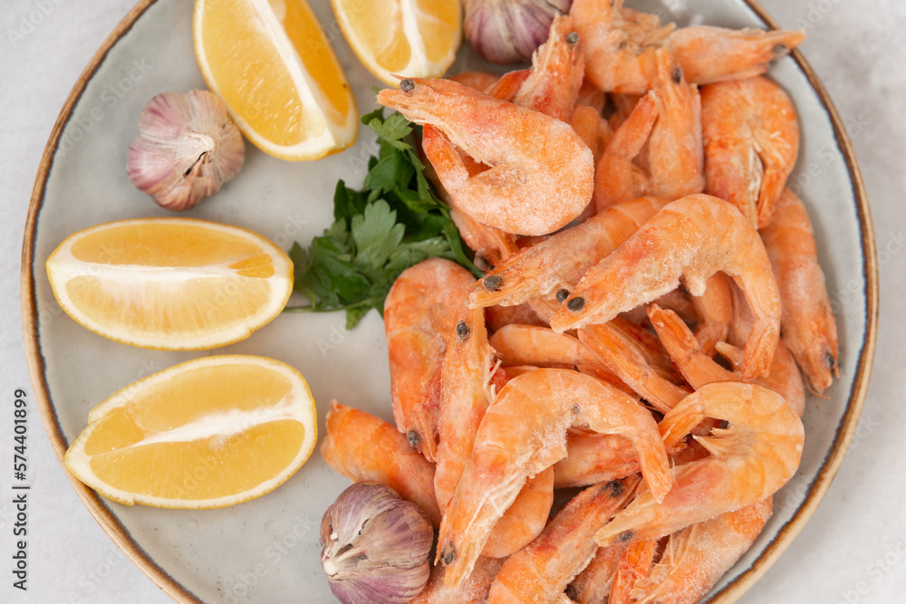 frozen raw shrimps with lemon and garlic on a gray rock background frozen raw shrimps with lemon and garlic on a gray rock background