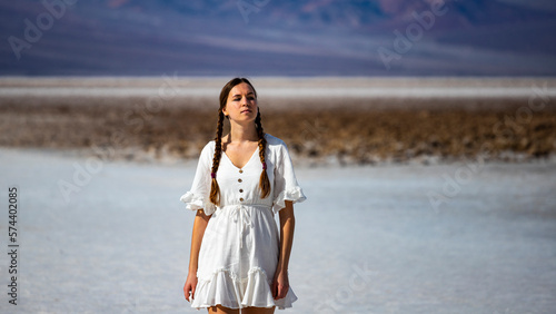 beautiful native american girl walking on the salt flats in badwater basin, death valley national park, california, usa; girl with pigtails in lace dress