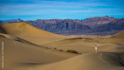 girl in white dress lost in the desert  walking on large sand dunes in mesquite flat sand dunes in death valley national park  california  usa