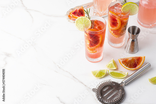 Pink Paloma with red blood orange and tequila on a marble table, barman tools and props. Summer refreshing cocktails
. 