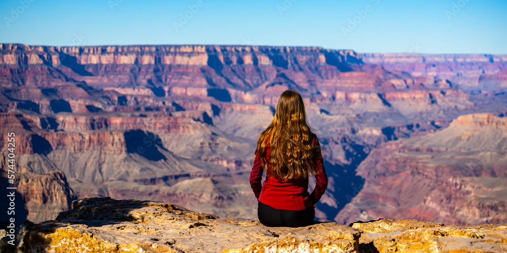 long haired hiker girl sitting on the edge of grand canyon; hiking in ...